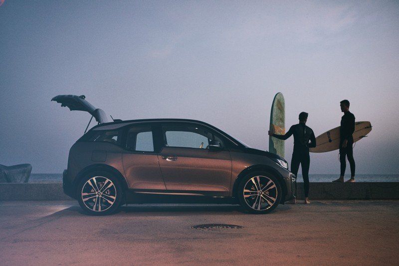 BMW i3 stehend neben zwei Surfer